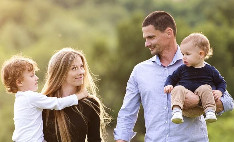 Man and woman each holding a toddler and looking in each other's eyes.