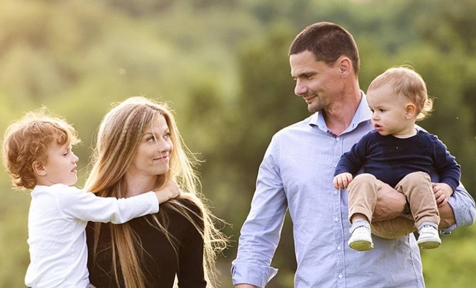 Man and woman each holding a toddler and looking in each other's eyes.